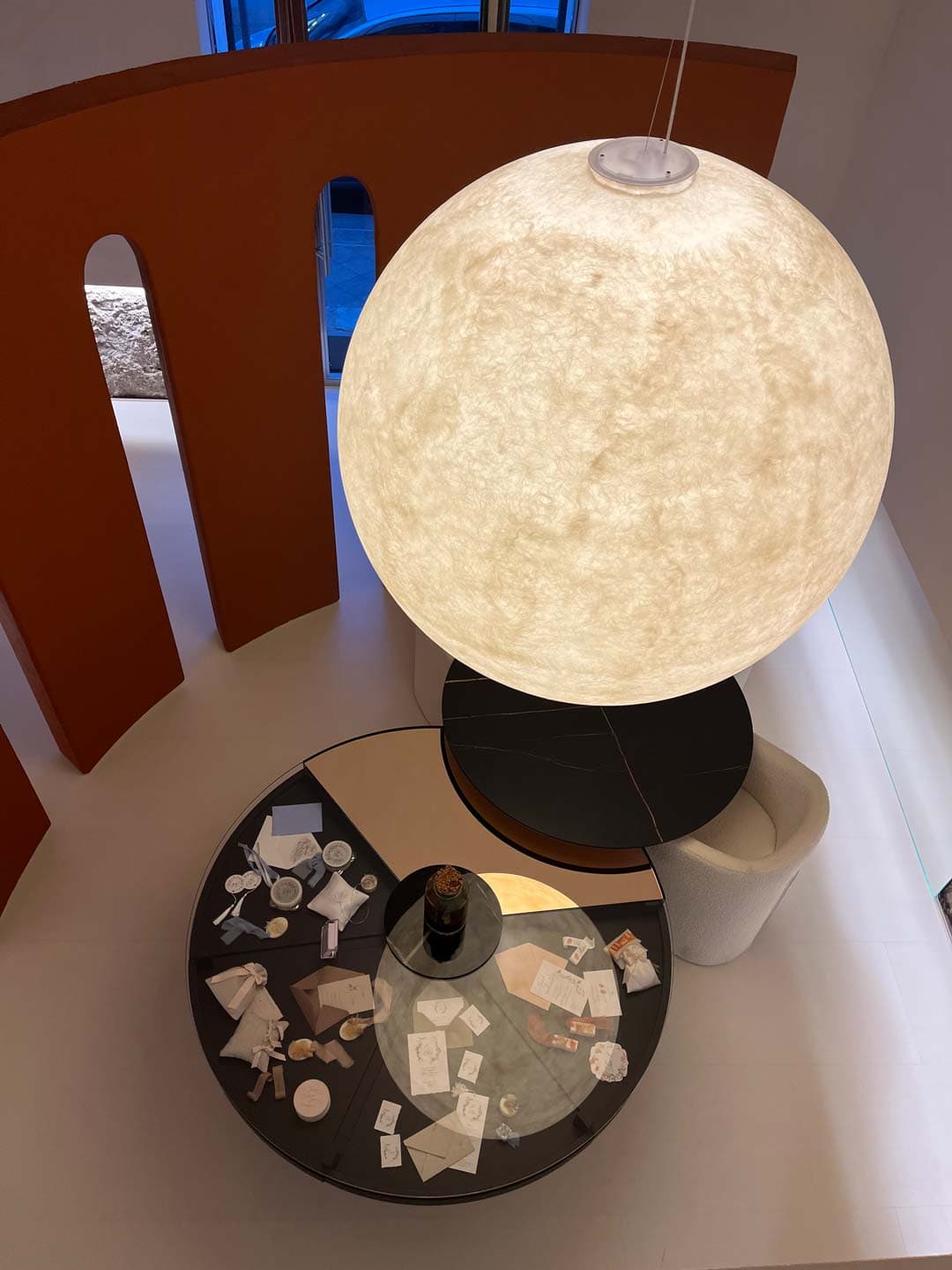 A large spherical light hangs over a round table and a white chair.