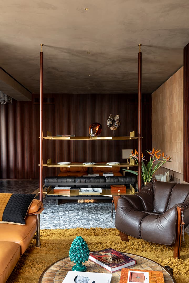 Modern living room with leather chairs, a coffee table, and a decorative shelving unit. Warm tones and textured rug enhance the cozy atmosphere.